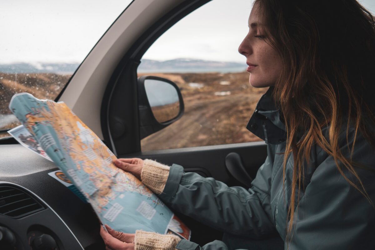 Islande, jeune femme dans une voiture regardant une carte