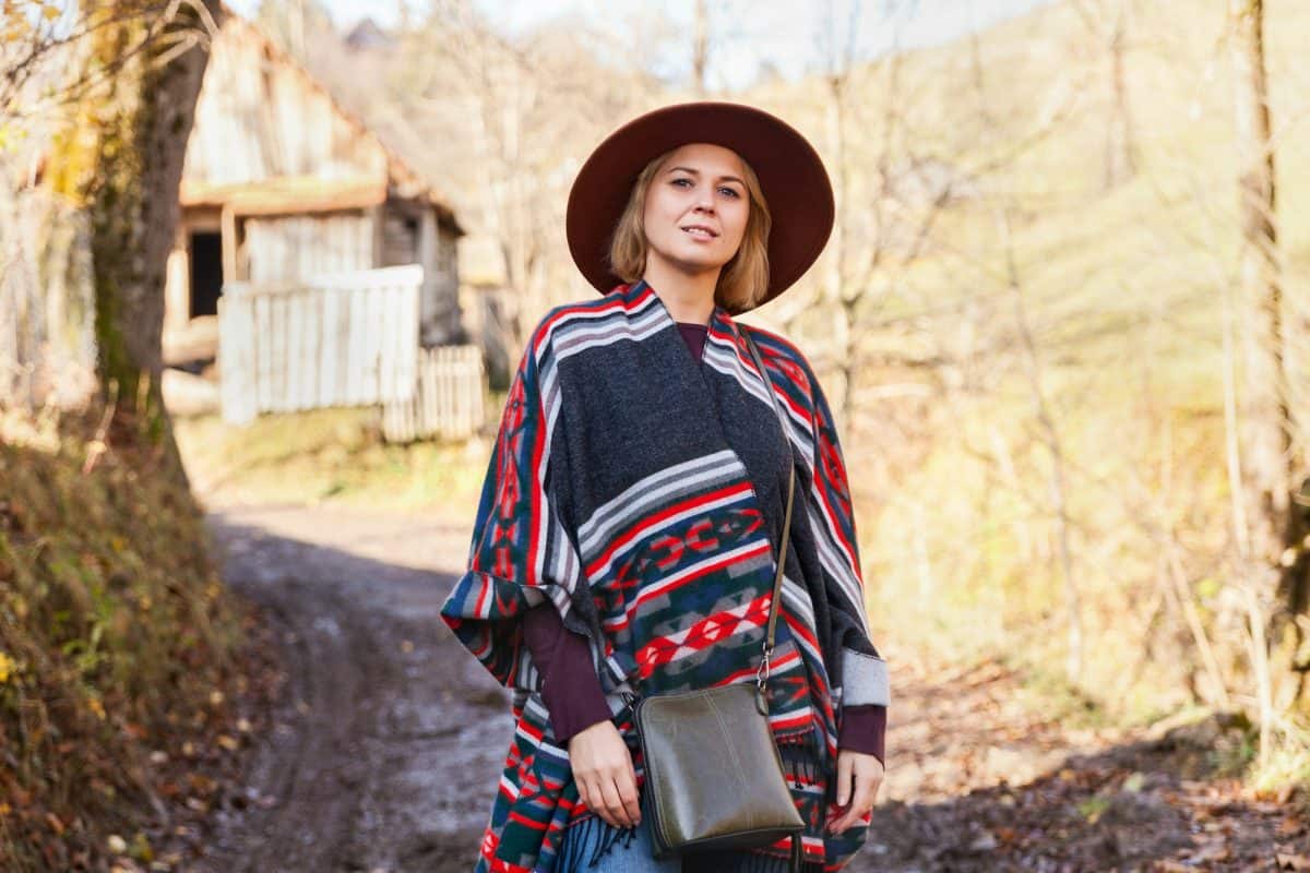 Stylish hipster traveling woman wearing authentic boho chic style poncho and hat