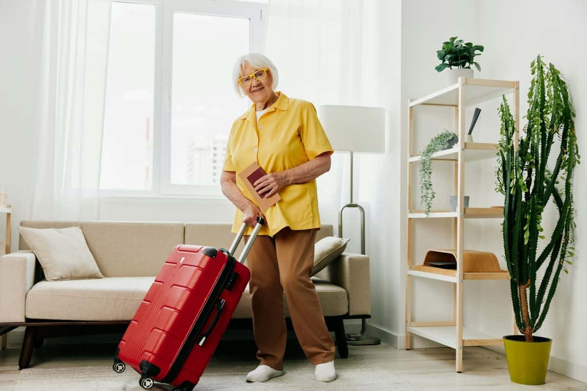 A happy elderly woman with a passport and a travel ticket in a red suitcase, vacation and healthcare