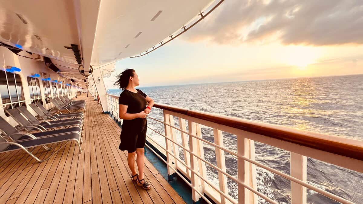 Vue arrière d'une femme debout sur la plage contre le ciel au coucher du soleil